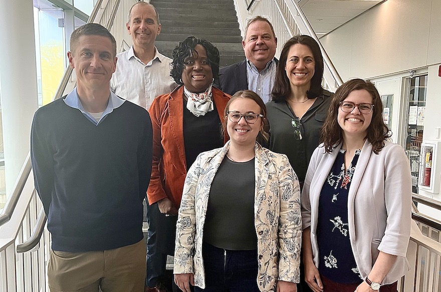7 people standing in building with stairs behind them