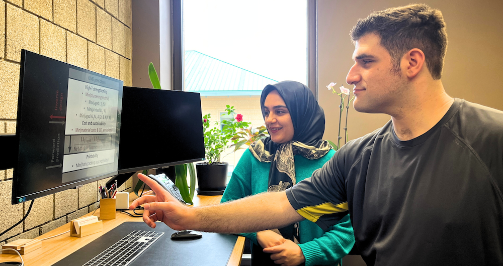Student pointing at computer screen with faculty member watching 