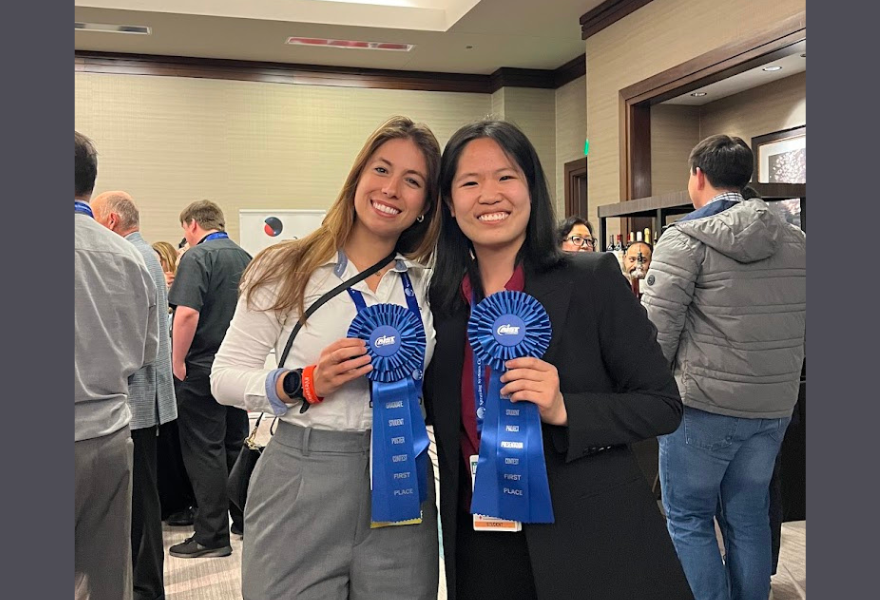 Two women holding blue ribbons 