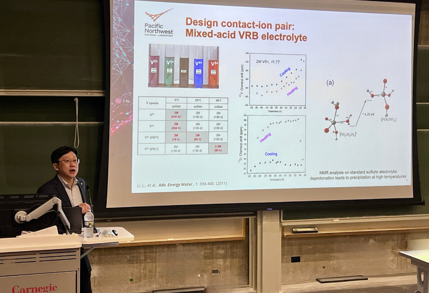 Wei Wang standing at podium in front of screen with slide