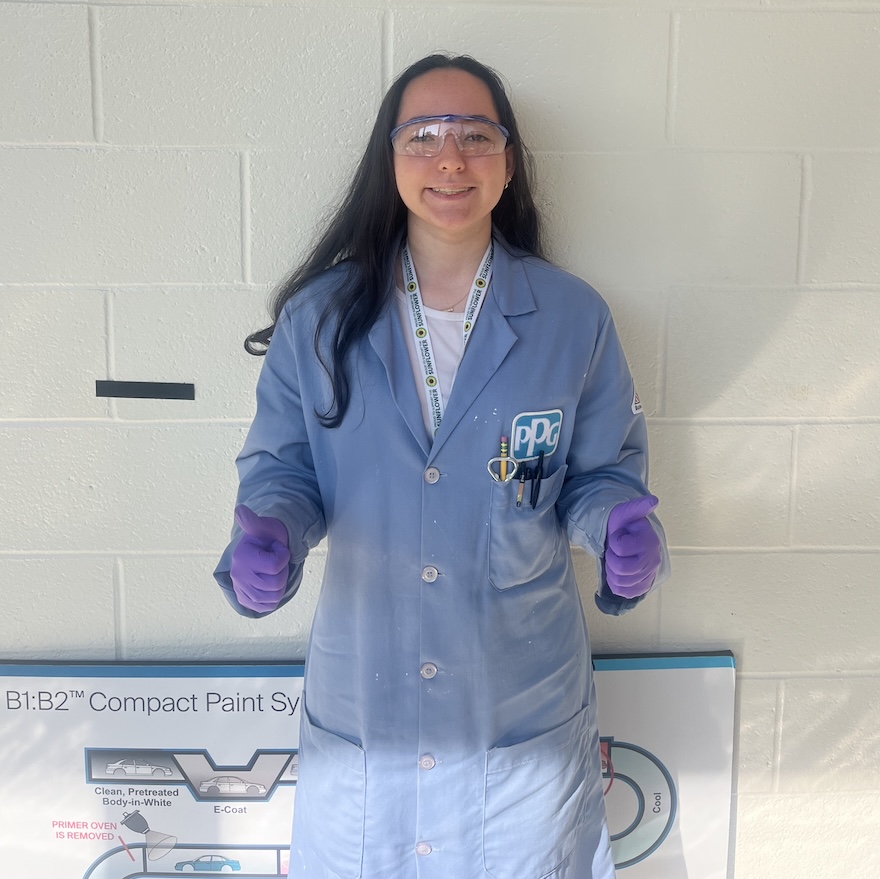 Student wearing lab coat and giving thumbs up